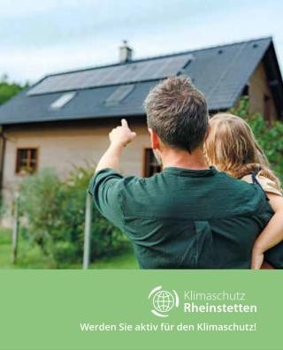 Mann mit Kind auf dem Arm zeigt auf ein Haus mit Photovoltaikanlage