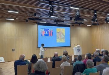 Dr. Katja Förster vor einer Leinwand und zahlreichen Zuschauern