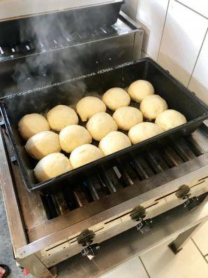 15 dampfende Dampfnudeln in einem Bräter auf einem Gaskocher