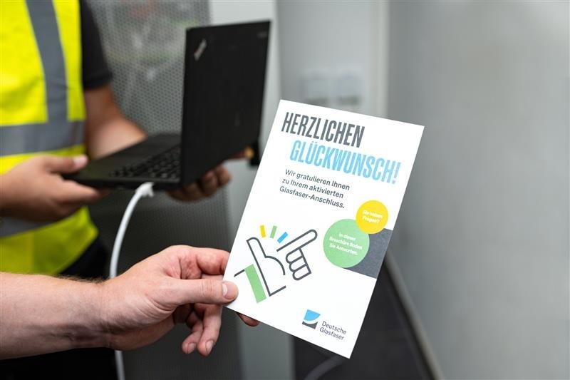 Hand hält Gratulationskarte zum Glasfaseranschluss